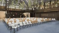 Modern event hall with rows of white chairs, a stage with geometric shapes, and an illuminated 'FUSION HALL' sign