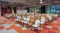 Blick durch die Crossover Stage im Smartvillage B-NK mit bunter Teppichgestaltung und Stuhlreihen.
