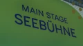 Beschilderung „Main Stage Seebühne“ auf grünem Hintergrund mit blauen Buchstaben.