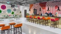 Wall with colorful circular art installations and a seating area with light green tables and chairs.
