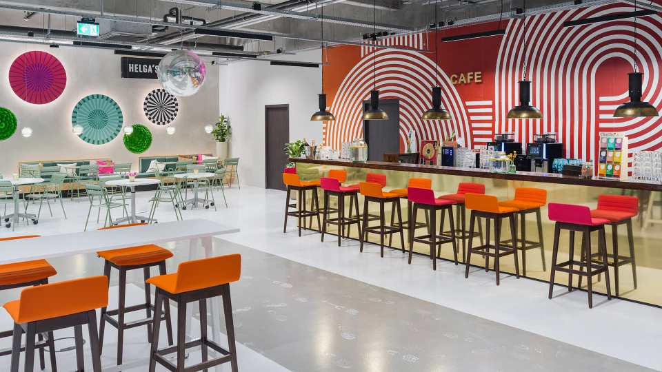 Wall with colorful circular art installations and a seating area with light green tables and chairs.