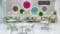 Modernly designed bar with green and white furniture, decorated with colorful wall fans and labeled 'Helga's Bar'.