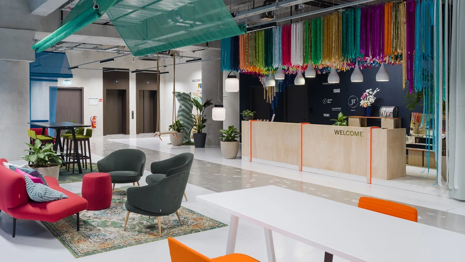 Eingangsbereich mit einem dekorierten Buddy Bären, Festival-Wegweiser an der Wand und einer Holzbox.