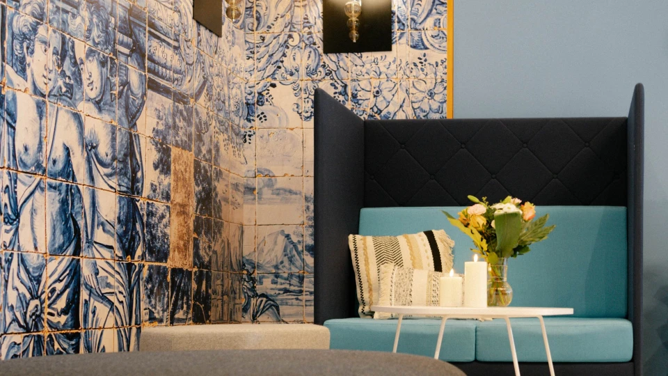 Gemütliche Lounge-Ecke mit hoher Sitzbank, Kissen und Blumen, umgeben von kunstvollen blauen Fliesen