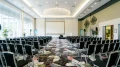 Symmetrischer Blick auf den Konferenzraum Wien mit zentraler Projektionsfläche, LED-Kronleuchter und großer Fensterfront.