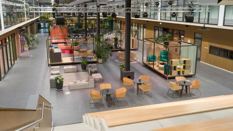 Eventfläche mit mobilen Arbeitsmodulen, Pflanzen und bunten Besprechungsräumen im smartvillage Köln