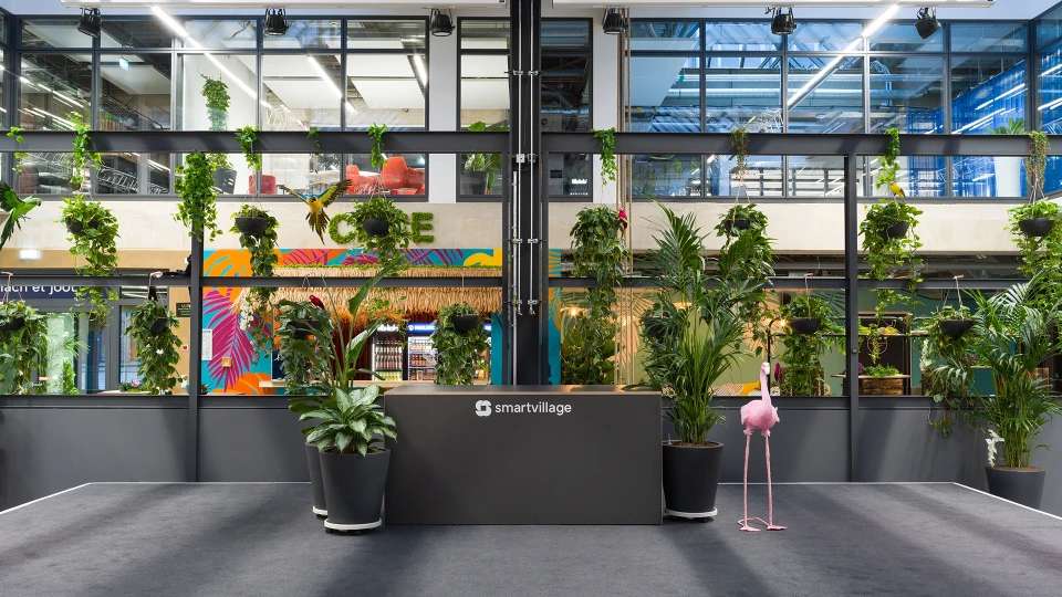 Empfangsbereich mit Pflanzenwand, Papagei-Deko und smartvillage-Logo