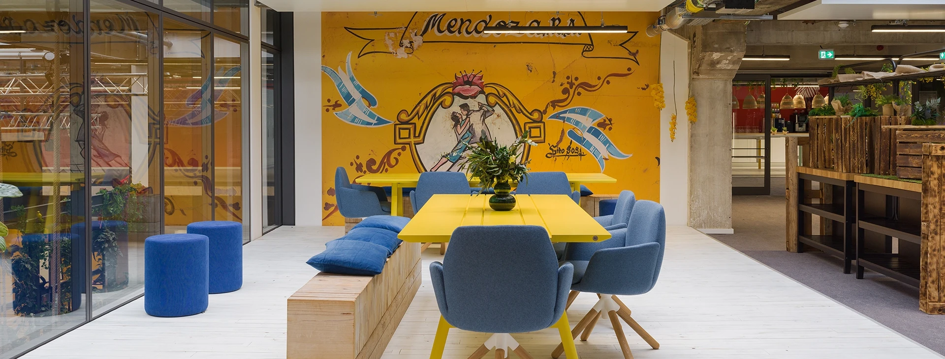 Creatively designed meeting area with wall graphic and yellow table in Smartvillage Cologne Mülheim
