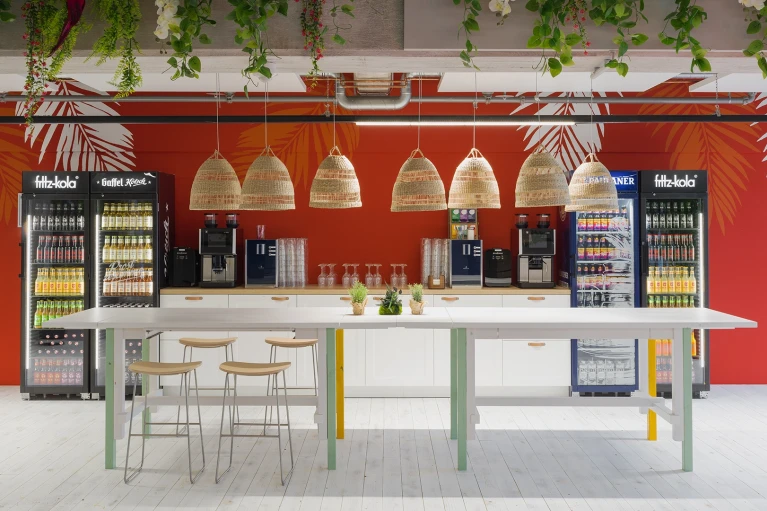 Übersicht über die Beachbar im Smartvillage Köln-Mülheim mit Hängelampen, Pflanzen und buntem Interieur.