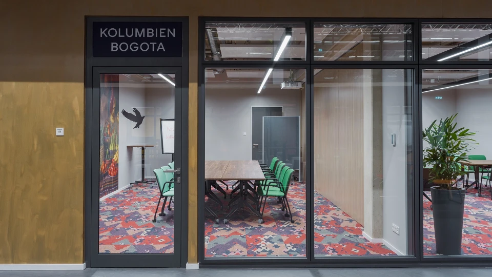 Meetingraum Kolumbien Bogota mit farbenfrohem Teppich, Glastür und moderner Einrichtung im Smartvillage Coworking Space