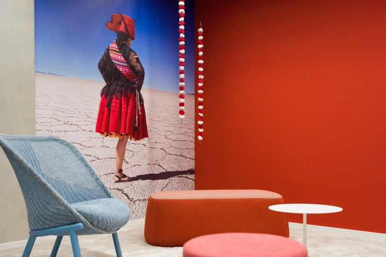 Detailansicht des Lounge-Bereichs im Raum Bolivien mit Wandbild einer bolivianischen Frau in traditioneller Kleidung im Smartvillage Köln