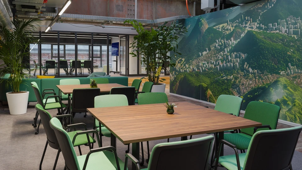 Lounge-Bereich im Raum Brasilien mit grünen Sofas, gelben Kissen und Fotowand von Rio de Janeiro im Smartvillage Köln-Mülheim