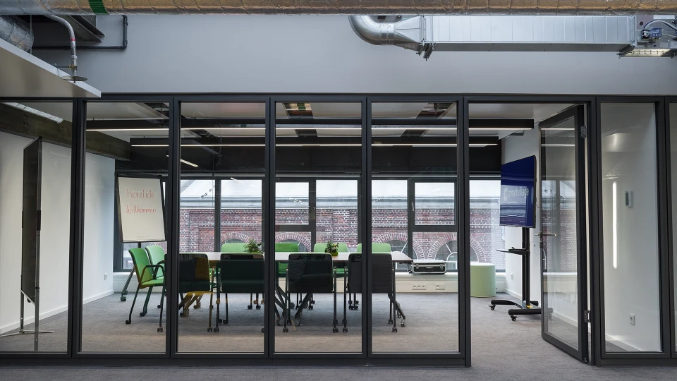 Breakout-Area im Raum Brasilien mit farbenfrohen Lounge-Möbeln und Blick auf die Präsentationsfläche im Smartvillage Köln