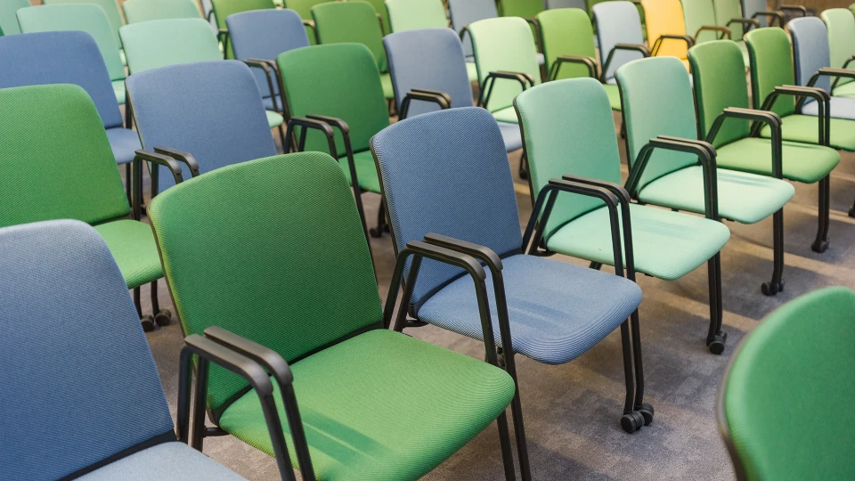 Reihen bunter Stühle im Konferenzbereich, angeordnet für eine größere Veranstaltung oder Präsentation.