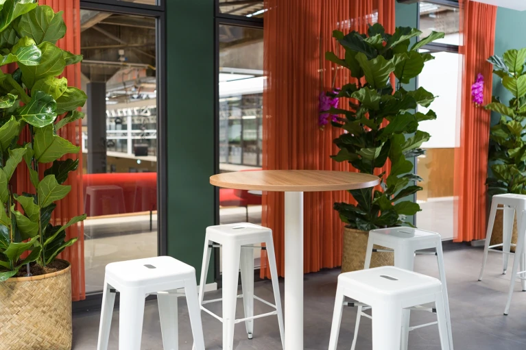 Hochtische mit weißen Barhockern in der Jungle Lodge im Smartvillage Köln Mülheim.