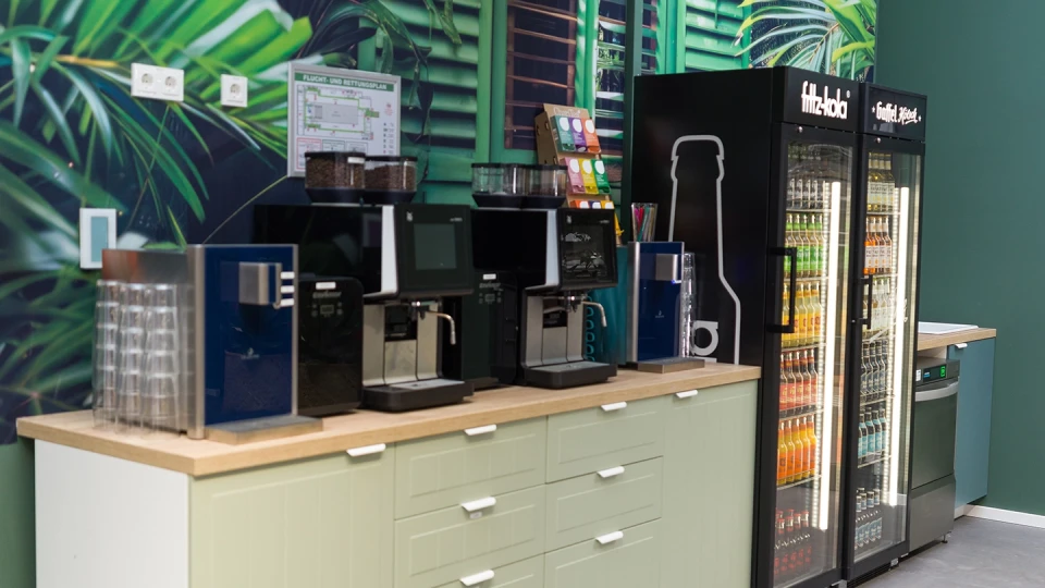 Detailaufnahme der Kaffee- und Getränkestation mit grünem Dschungelwandmotiv.