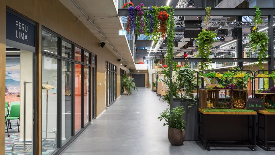 Flur im smartvillage Köln-Mülheim mit Blick auf die Tagungsräume PERU LIMA und PERU CUSCO sowie grün dekorierter Catering-Station