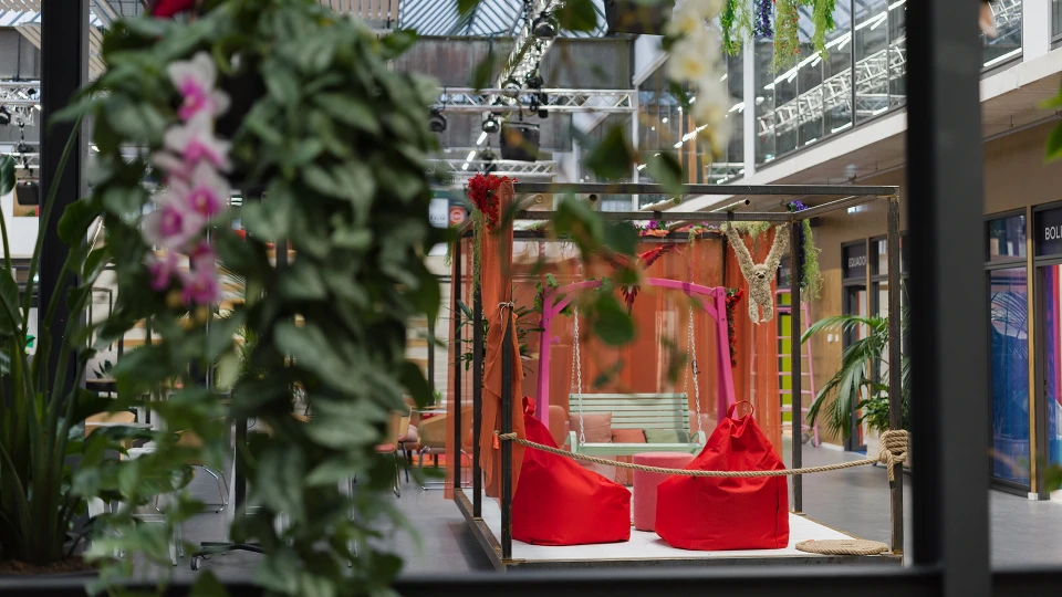 Gemütlicher Sitzbereich im Smartcafé mit Wand in Türkis und dekorativen Wandblättern, ergänzt durch moderne Hocker und Tische.