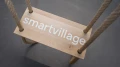 Nahaufnahme einer Holzschaukel mit dem Schriftzug "smartvillage" auf der Sitzfläche.