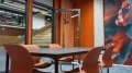 View of the door and table in the 'Suriname' meeting room, with a view into the atrium and wall art.