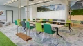 Modernes Büro mit einem langen Tisch und grünen sowie grauen Stühlen, Schaukeln an der Decke und Bergpanorama-Wandbild