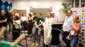 Gruppe von lächelnden Personen verschiedener Altersgruppen in einem Büro während eines Workshops mit Stühlen, Post-its und einem Flipchart